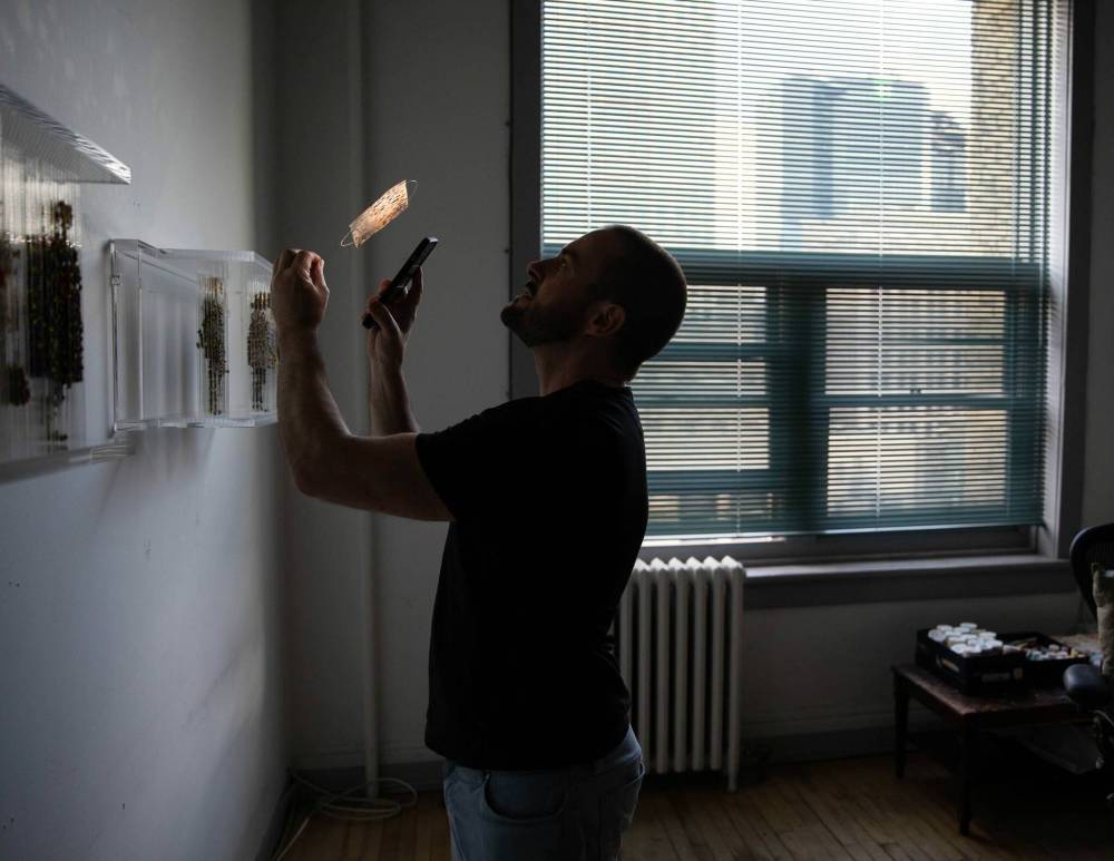 JESSICA LEE / WINNIPEG FREE PRESS Chris Dorosz shows an example of a newspaper clipping which he has poked holes into on November 1, 2021 in his studio in downtown Winnipeg. The viewer is meant to manipulate the piece using a flashlight and make shadows on a wall.