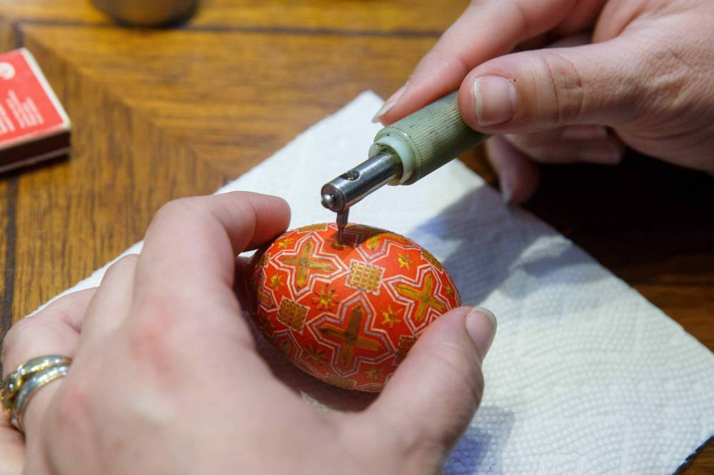 Rossier dyes, then puts a final layer of beeswax on a pysanka.