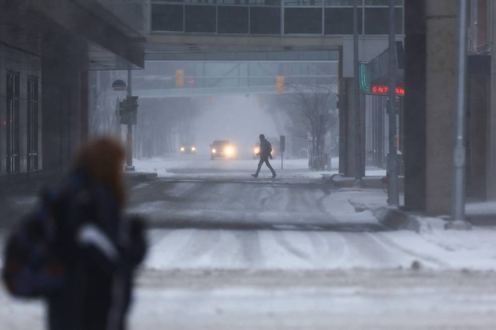Pedestrians take on a blustery snowfall as they cross Hargrave Street early Wednesday morning. (Mike Deal / Winnipeg Free Press)