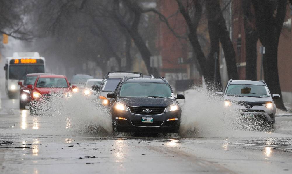 Cars drive through water on Sherbrook Street on Sunday. (John Woods / Winnipeg Free Press)