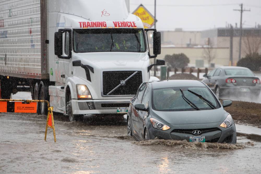 Motorists navigate deep water and a large hidden pothole on Route 90 just north of Dublin Avenue in Winnipeg on Saturday. (Daniel Crump / Winnipeg Free Press)