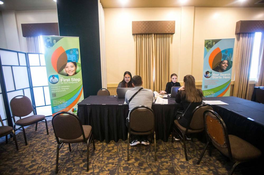 Jasmine San Miguel (left) and Khrystyna Horbay, intake advisors with Manitoba Start, help newcomers at the Ukrainian refugee reception centre in Winnipeg. (Winnipeg Free Press photos)