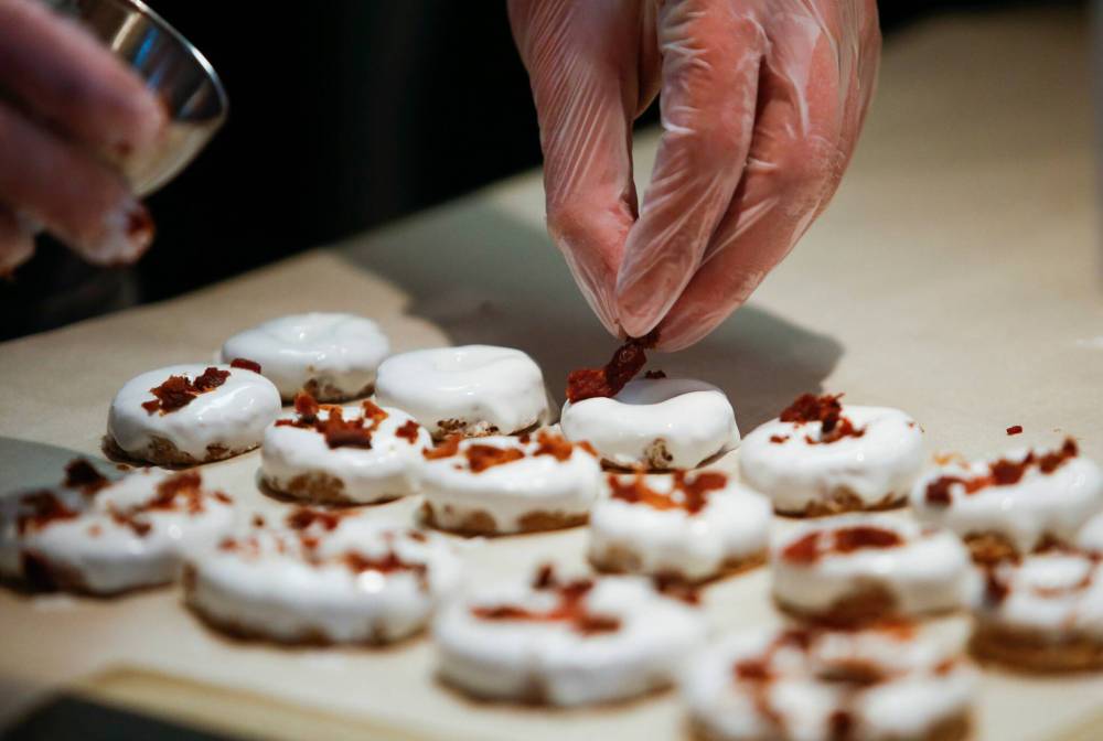 JOHN WOODS / WINNIPEG FREE PRESS The finishing touch of real bacon is added to an order of “The Canuck” doughnuts.