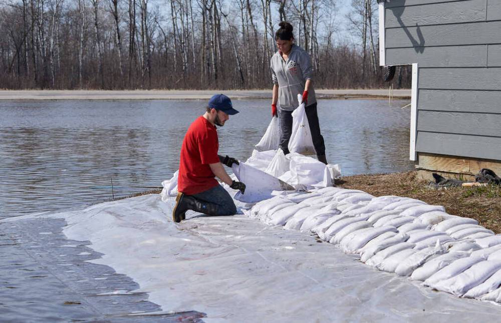DAVID LIPNOWSKI / THE CANADIAN PRESS FILES
Rebecca Sutherland of Pequis First Nation, and Shaine Paul from Red Rose volunteer to sandbag a home at risk of flooding in Peguis.