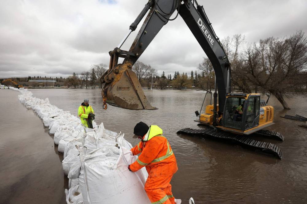 Noah Hofer and Tony Wollmann from Spring Hill Hutterite Colony help construct a super sandbag dike on Wednesday to protect Minnedosa Collegiate. (Tim Smith / The Brandon Sun)