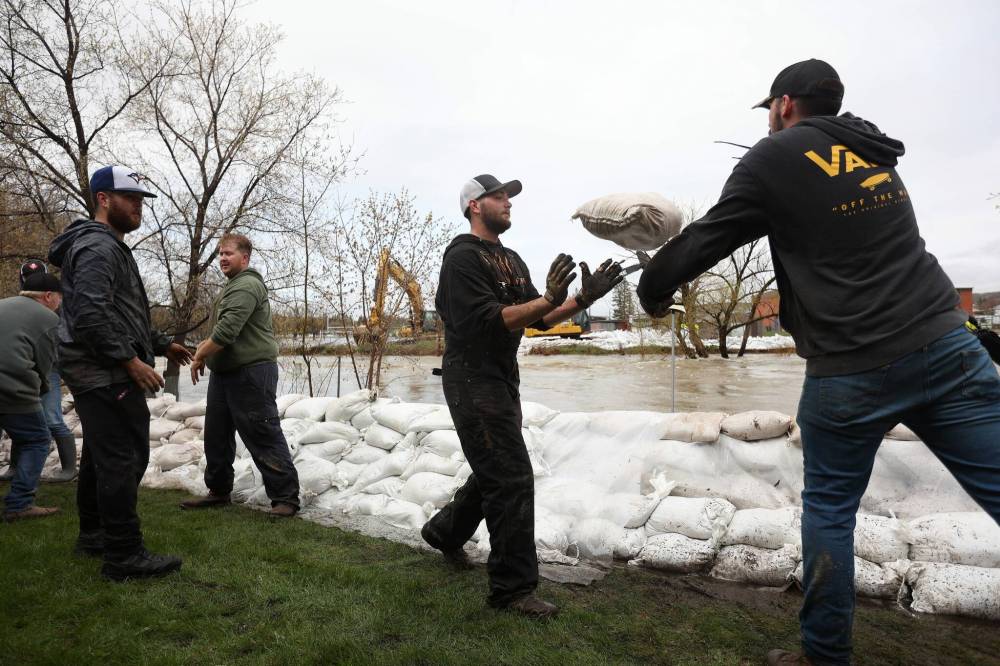 Volunteers sling sandbags to create a dike to protect homes in Minnedosa. (Tim Smith / The Brandon Sun)