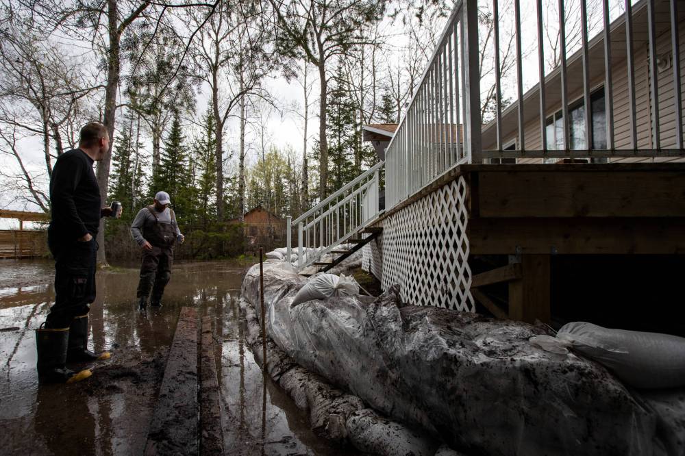 Dan Thomas and Colin Spark inspect a ring of sandbags they helped put up to fend off the waters of Eleanor Lake. (Daniel Crump / Winnipeg Free Press)