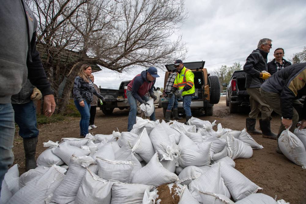 Community members in the Whiteshell area work together to help each other load sandbags into their vehicles. (Daniel Crump / Winnipeg Free Press)