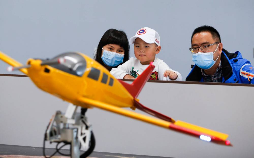 Binbin Cao, left, and Zhongwei Zou watch as their son Austin controls a model Beechcraft. (John Woods / Winnipeg Free Press)