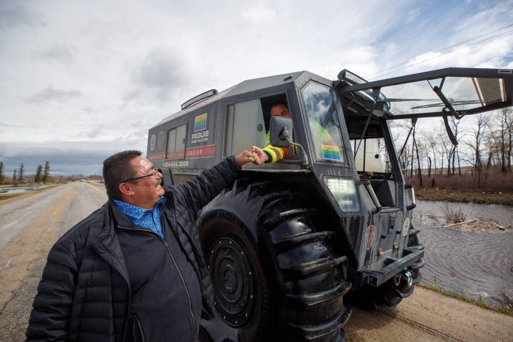 Peguis First Nation Chief Glenn Hudson fist bumps the crew of the amphibious vehicle that is being used to check in on residents. (Mike Deal / Winnipeg Free Press files)