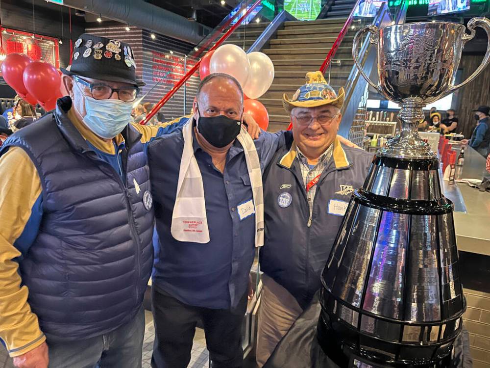 MELISSA MARTIN / WINNIPEG FREE PRESS
Bombers fans Victor Switzer, Dave Kolochuk and Hank Huewan pose with the Grey Cup at the Calgary Grey Cup Committee’s party on Thursday night. The three have a combined 73 Grey Cup experiences between them.