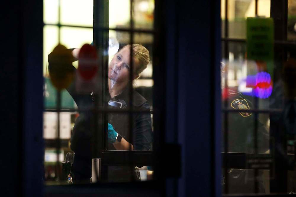 Police dusts for prints as they investigate the robbery at the Tyndal Market Liquor Mart. (John Woods / Free Press files)
