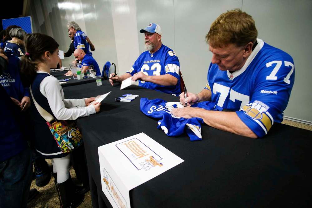 Winnipeg Blue Bomber alumni Chris Walby (left) and Stan Mikawos (right) sign autographs for fans Saturday at the convention centre. (Daniel Crump / Winnipeg Free Press)