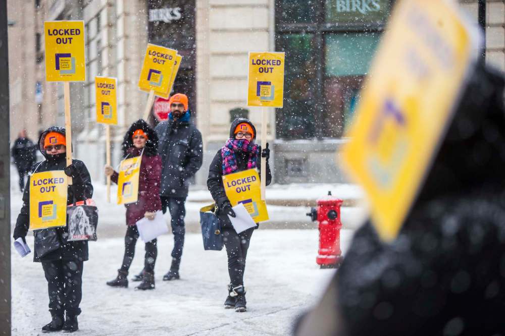 Cherry Garcia (centre) holds a sign at a rally of Tim Hortons employees outside of 1 Lombard Place on Friday. Fifteen workers at the restaurant were seeking a 30-cent increase in a recent round of collective bargaining. (Mikaela MacKenzie / Winnipeg Free Press)