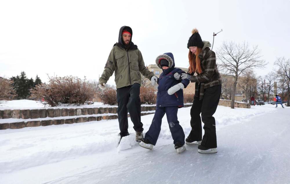RUTH BONNEVILLE / WINNIPEG FREE PRESS
Andrea Thidrickson and her boyfriend, Kevin Barkley, help his son, Dallas, 8, to skate at Arctic Glacier Winter Park at The Forks during the holidays. t