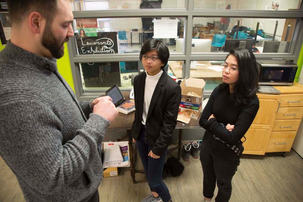 Students Rory Ramos (centre) and Alex Payawal talk to Maples Met principal Ben Carr about their writing project. (Melissa Martin / Winnipeg Free Press)