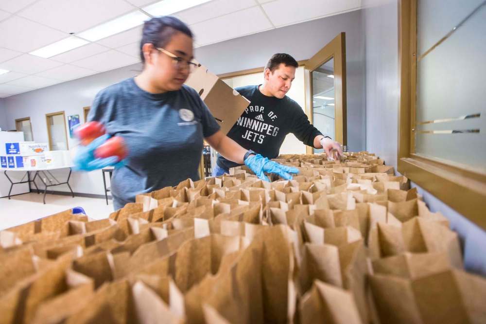 Volunteers Kyle Muswagon (right) and Tempest Bruce pack emergency kits at Ma Mawi Wi Chi Itata in Winnipeg on Monday. (Mikaela MacKenzie / Winnipeg Free Press)