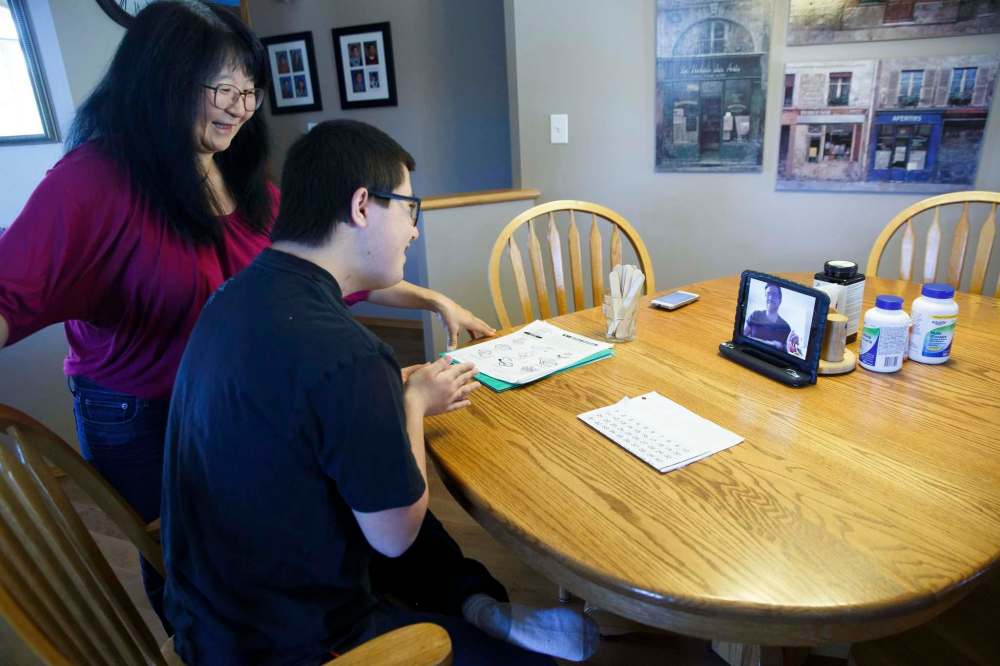 Daniel has a videoconference with his educational assistant as his mother, Cathy, looks on. (Mike Deal / Winnipeg Free Press)