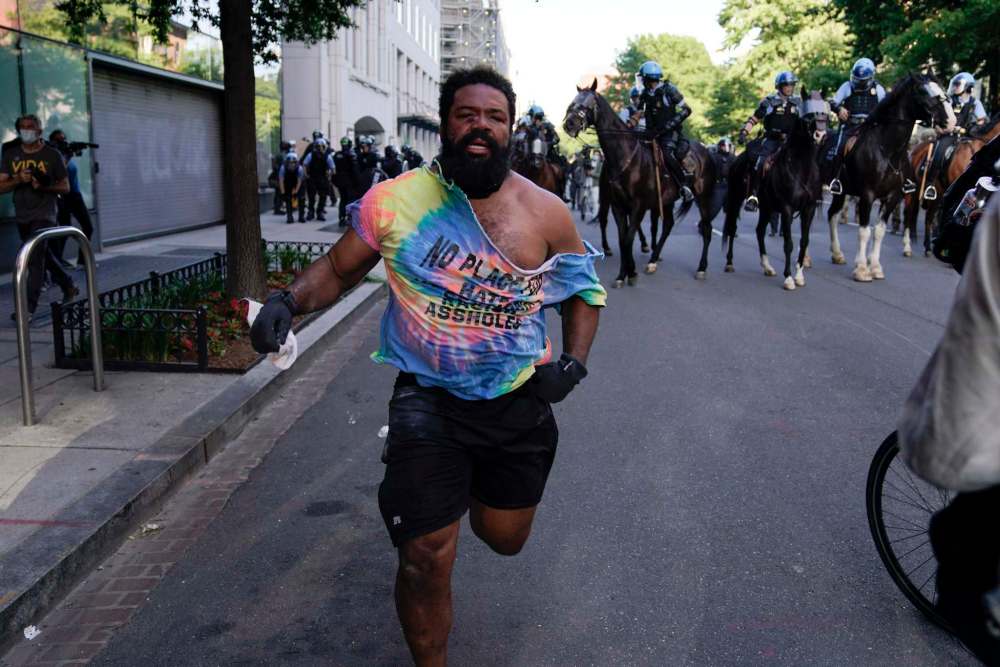 Evan Vucci / The Associated Press
A demonstrator and others who gathered to protest the death of Floyd Monday move away from police officers on horses near the White House in Washington.