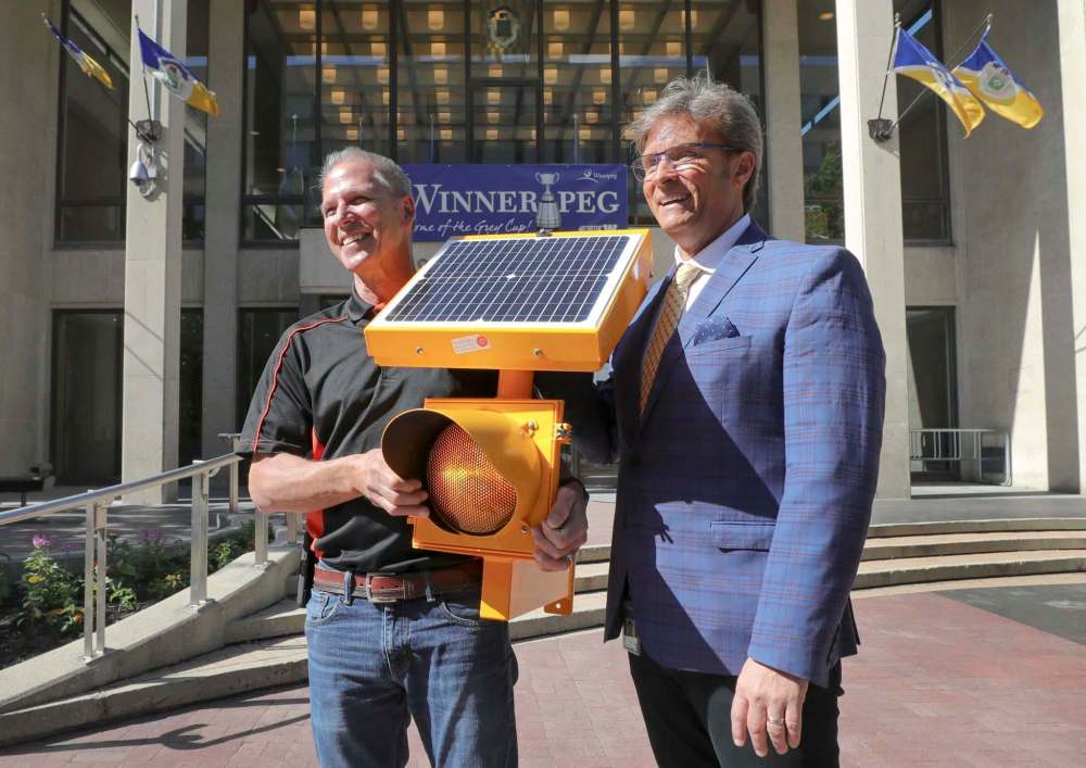 RUTH BONNEVILLE / WINNIPEG FREE PRESS Chuck Lewis of Expert Electric (left) & Councillor Kevin Klein outside city hall with one of Lewis' amber flashing lights.