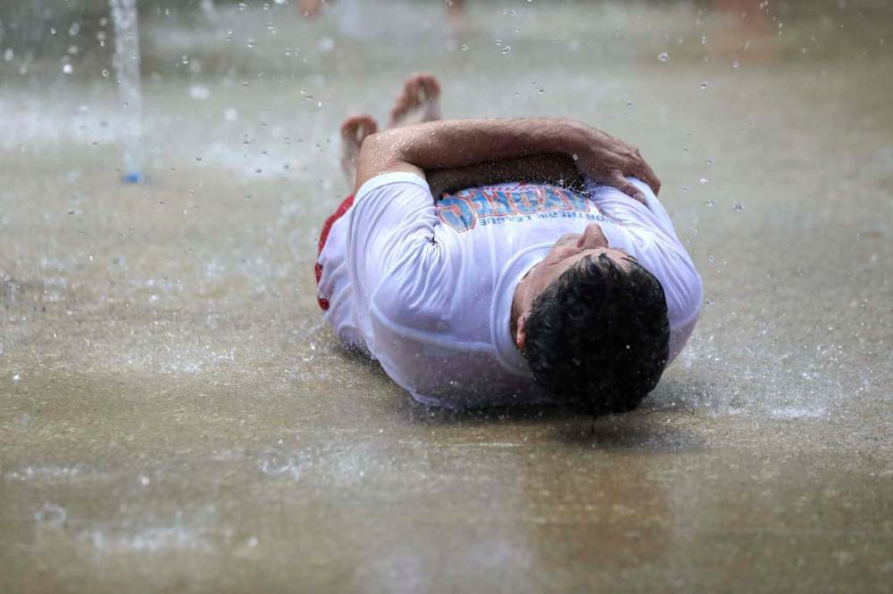 RUTH BONNEVILLE / WINNIPEG FREE PRESS
Luc Labelle cools himself while spending time with his godchild at Provencher Park Spray Pad during the heat wave on Monday.