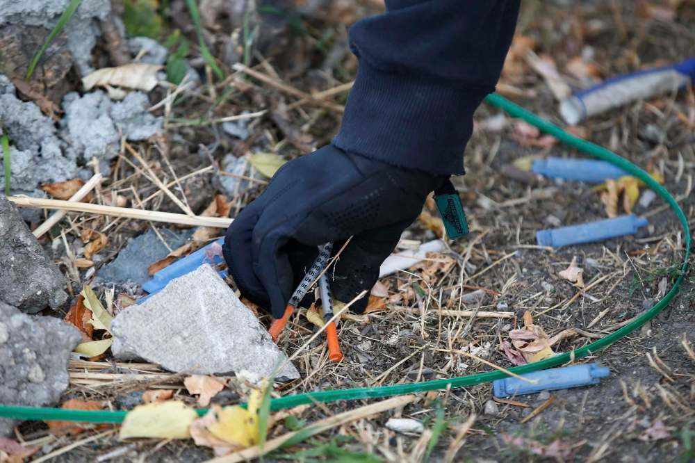 Team members look for discarded needles and dispose of them in sharps containers donated to them by Street Connections.