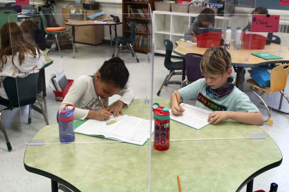 MAGGIE MACINTOSH / WINNIPEG FREE PRESS
Students Faith, left, and Ricky sit at their desks, separated by plexiglass dividers.