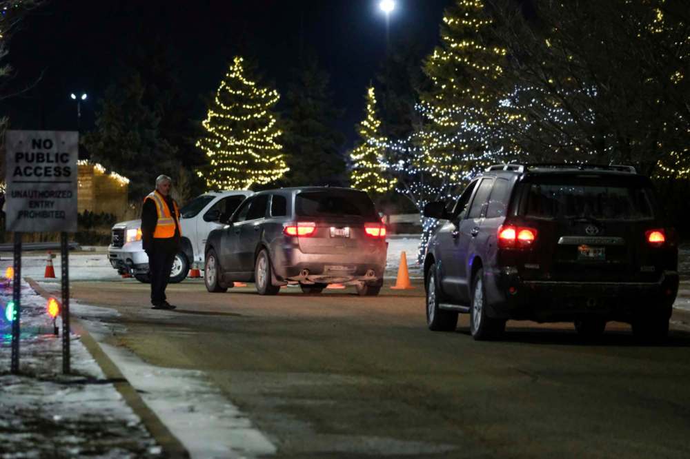 Daniel Crump / Winnipeg Free Press
Church Springs private security stands guard as vehicles line up to attend a drive-in church service on Saturday.