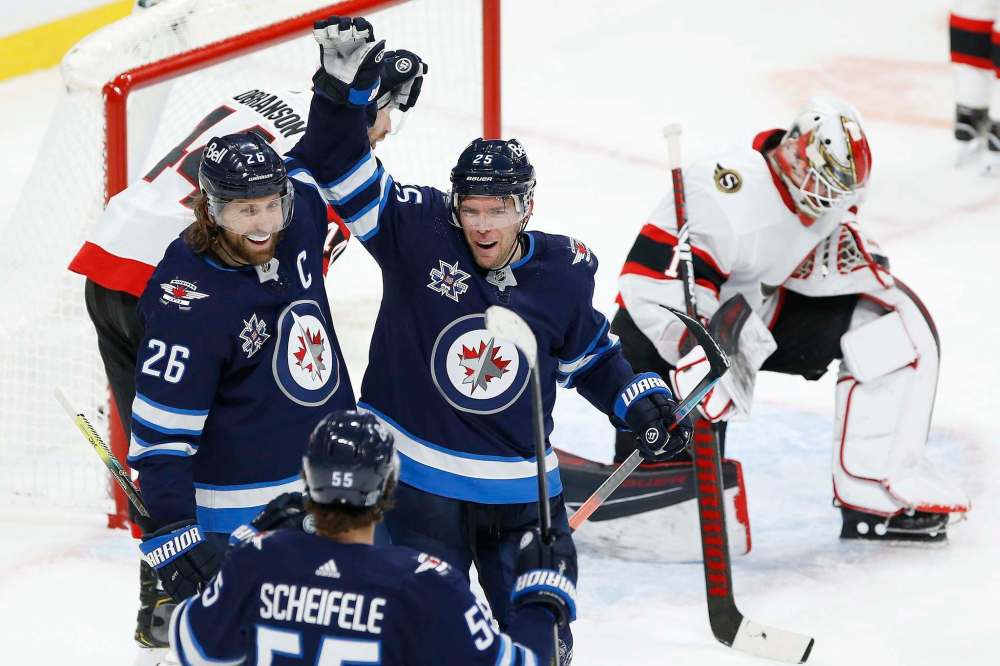 Winnipeg Jets' Mark Scheifele (55), Blake Wheeler (26) and Paul Stastny (25) celebrate Stastny's game winning goal against Ottawa Senators goaltender Marcus Hogberg (1) during third period NHL action in Winnipeg on Saturday, January 23, 2021. THE CANADIAN PRESS/John Woods