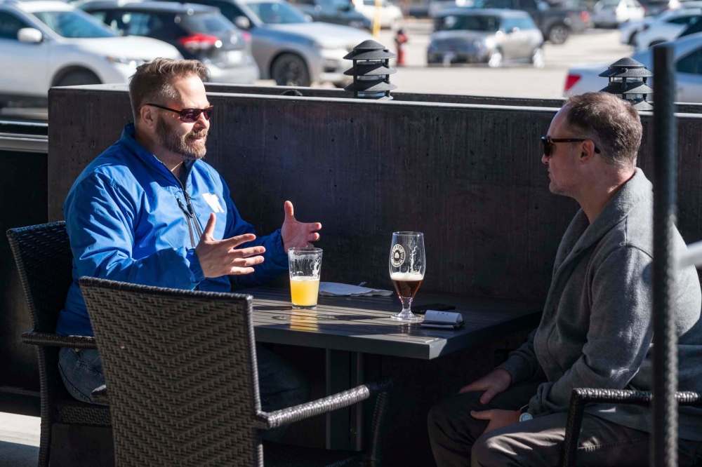 Trevor Finch (left) had a drink with his neighbour Paul Thomas on the patio at Fionns on Grant Avenue. (Daniel Crump / Winnipeg Free Press)