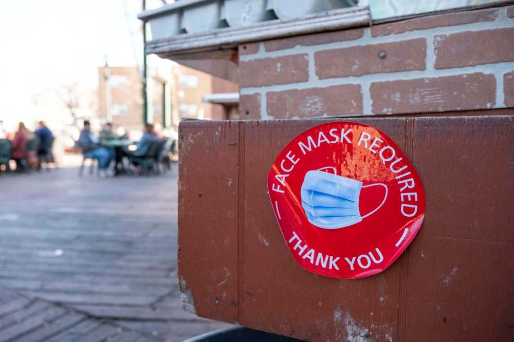 A sign on the patio at Saffrons on Corydon reminds customers to wear masks. Masks are still required at restaurants unless seated at a table. (Daniel Crump / Winnipeg Free Press)