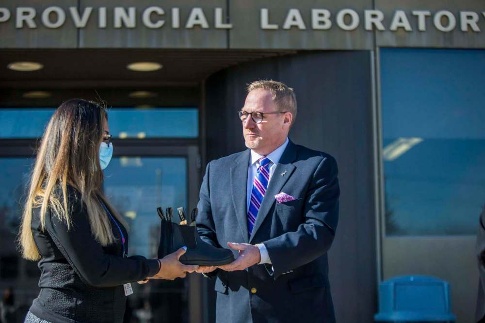 MIKAELA MACKENZIE / WINNIPEG FREE PRESS
Finance minister Scott Fielding hands laboratory technician Chaturika Mesgun a pair of shoes at Cadham Provincial Laboratory.