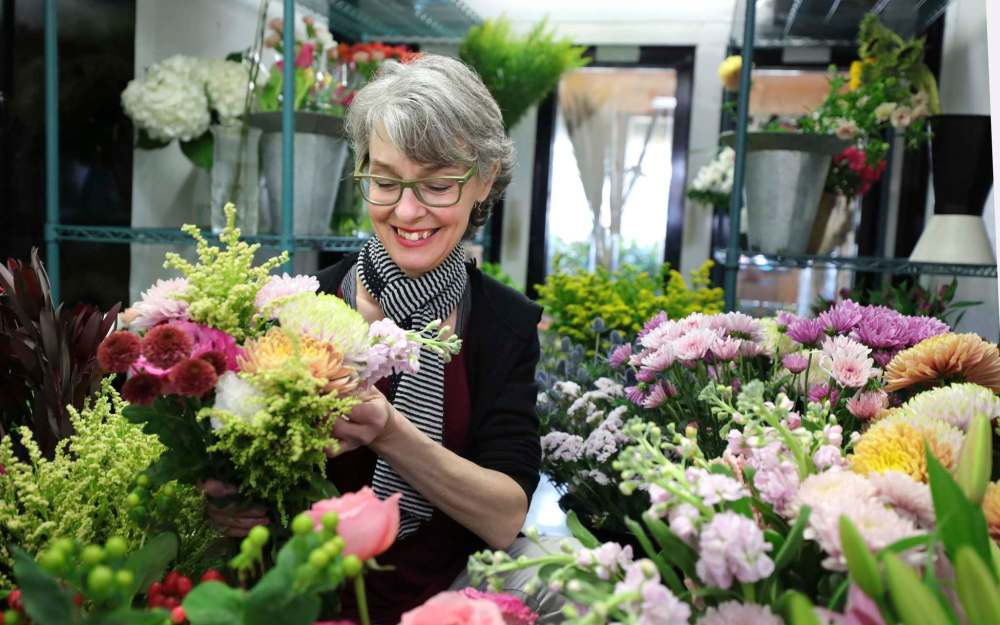 RUTH BONNEVILLE / WINNIPEG FREE PRESS Biz - Norwood Florist Photo of Michele Pitre, owner of Norwood Florist Design Studio, scene through the doors of her fridge full of beautiful flowers as she puts together a bouquet for a customer on Tuesday. Subject: Story on pandemic supply chain issues that florists are facing heading into Mothers' Day, the busiest week of the year for the industry. Business has been up by 30 per cent during the past year because people are sending more flowers since they can't meet in person. But Pitre at Norwood Florists asks customers to be patient because sometimes she doesn't even know what she's getting form the wholesalers April 27, 2021