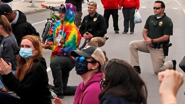 Lt. Alex Reno, of the Hampton, N.H. police department, right, and Dep. Chief Kevin Gelineau, of the Seabrook, N.H. police department, center, take a knee as they join with protesters taking a knee during a rally, Monday June 1, 2020 on Hampton Beach. The group gathered to voice their concerns following the death of George Floyd, who died after being restrained by Minneapolis police officers on Memorial Day. (AP Photo/Charles Krupa)