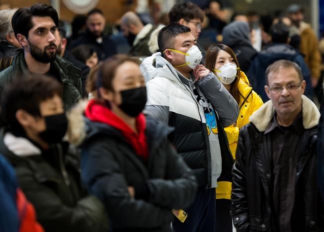 People wear masks as a precaution due to the coronavirus outbreak as they wait for the arrivals at the International terminal at Toronto Pearson International Airport in Toronto on Saturday, January 25, 2020. Canadian health officials announced a first presumed case in Ontario after the illness has sickened more than 1,200 people and killed at least 41 in China, the epicentre of the outbreak. THE CANADIAN PRESS/Nathan Denette