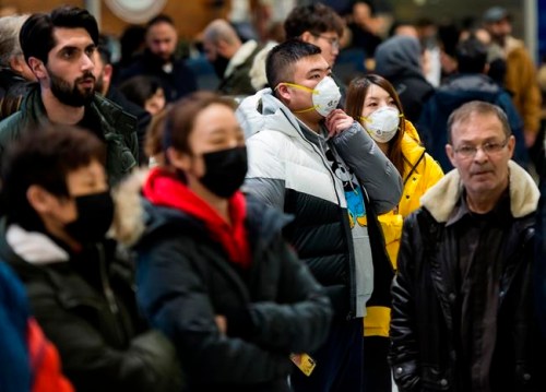 People wear masks as a precaution due to the coronavirus outbreak as they wait for the arrivals at the International terminal at Toronto Pearson International Airport in Toronto on Saturday, January 25, 2020. Canadian health officials announced a first presumed case in Ontario after the illness has sickened more than 1,200 people and killed at least 41 in China, the epicentre of the outbreak. THE CANADIAN PRESS/Nathan Denette