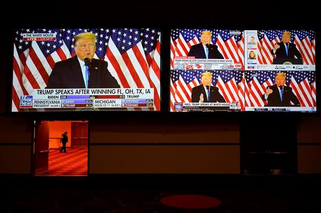 A live broadcast of President Donald Trump speaking from the White House is sown on screens at an election night party, Tuesday, Nov. 3, 2020, in Las Vegas. (AP Photo/John Locher)