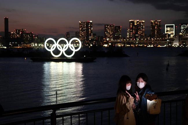 Two women take a selfie with the Olympic rings in the background in the Odaiba section of Tokyo, Thursday, March 12, 2020. Tokyo Governor Yuriko Koike spoke Thursday after the World Health Organization labeled the spreading virus a