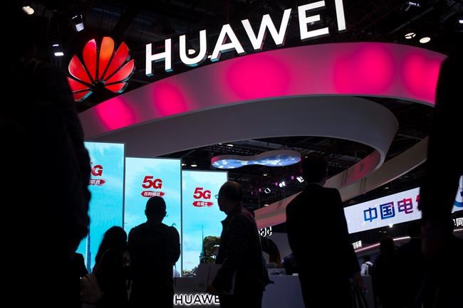 FILE - In this Oct. 31, 2019, file photo, attendees walk past a display for 5G services from Chinese technology firm Huawei at the PT Expo in Beijing. The Trump administration is stepping up pressure on European allies to ban Chinese tech firm Huawei from supplying next-generation mobile networks, with more officials visiting this week to press the case. (AP Photo/Mark Schiefelbein, File)