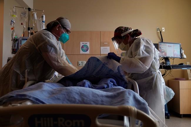 FILE - In this Dec. 22, 2020, file photo, registered nurses Robin Gooding, left, and Johanna Ortiz treat a COVID-19 patient at Providence Holy Cross Medical Center in the Mission Hills section of Los Angeles. Coronavirus deaths in the U.S. hit another one-day high on Tuesday, Jan. 12, 2021, at over 4,300 with the country’s attention focused largely on the fallout from the deadly uprising at the Capitol. (AP Photo/Jae C. Hong, File)