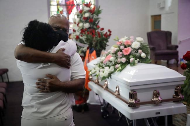 FILE - In this July 21, 2020, file photo, Darryl Hutchinson, facing camera, is hugged by a relative during a funeral service for Lydia Nunez, who was Hutchinson's cousin at the Metropolitan Baptist Church in Los Angeles. Nunez died from COVID-19. The U.S. death toll from the coronavirus topped 300,000 Monday, Dec. 14, just as the country began dispensing COVID-19 shots in a monumental campaign to conquer the outbreak. (AP Photo/Marcio Jose Sanchez, File)