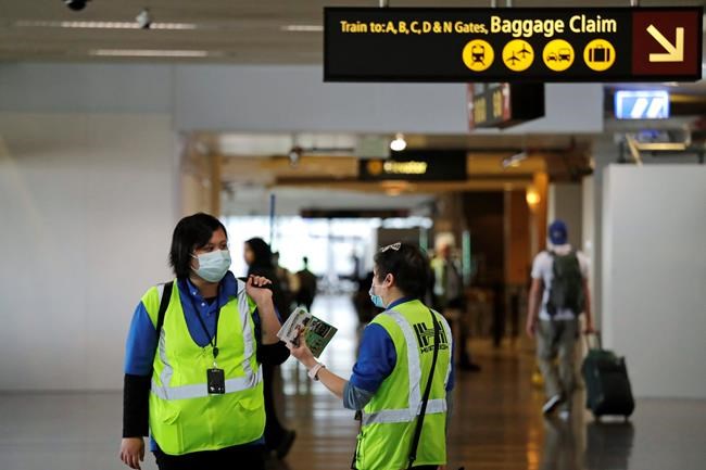FILE - In this Tuesday, March 3, 2020, file photo, a pair of workers at Seattle-Tacoma International Airport wear masks in SeaTac, Wash. While white collar workers trying to avoid contagion can work from home or call in sick if they experience symptoms of the new virus, such precautions are not an options for the millions of waiters, delivery workers, cashiers, ride-hailing drivers, museum attendants and countless others who routinely come into contact with the public. (AP Photo/Elaine Thompson, File)