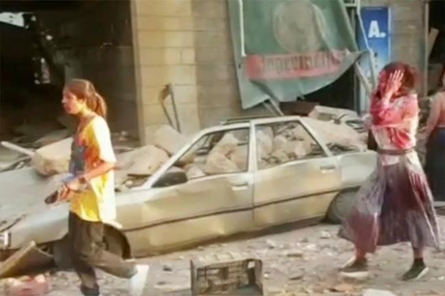 In this frame from video people walk down the street after an explosion in Beirut, Tuesday, Aug. 4, 2020. A massive explosion shook Lebanon's capital wounding a number people and causing widespread damage. (AP Photo)