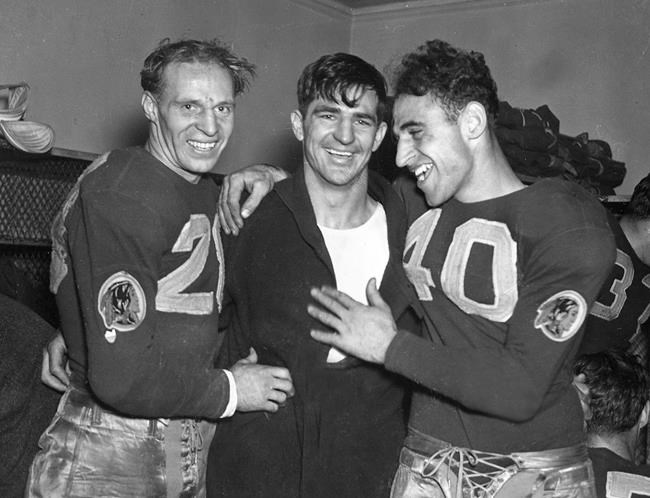 FILE - In this Dec. 12, 1937, file photo, Washington Redskins quarterback Sammy Baugh, center, celebrates with teammates Cliff Battles, left, and Wayne Millner in the locker room after the Redskins defeated the Chicago Bears 28-21 in the NFL championship football game in Chicago. Washington’s NFL team will get rid of the name