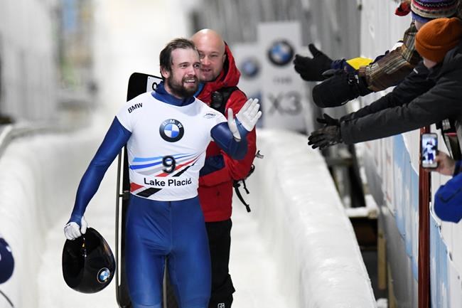 Alexander Tretiakov, of Russia, celebrates his first place finish in the men's skeleton World Cup race with fans in Lake Placid, N.Y., on Friday, Dec 13, 2019. (AP Photo/Hans Pennink)