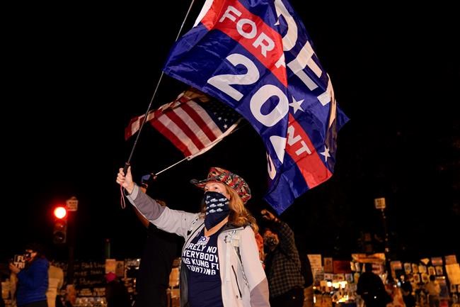 Jennifer Riggle, of Washington, waves flags in support of Democratic presidential candidate Joe Biden at Black Lives Matter Plaza, Wednesday, Nov. 4, 2020, in Washington. (AP Photo/Jacquelyn Martin)