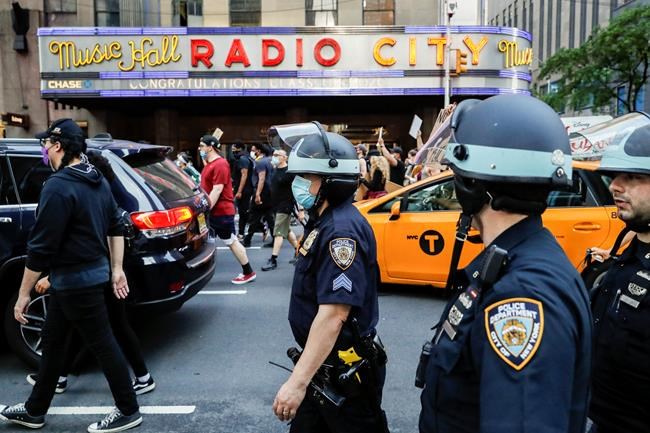 New York City police officers follow a group of protesters past Radio City Music Hall during a march Wednesday, June 3, 2020, in the Manhattan borough of New York. Protests continued following the death of George Floyd, who died after being restrained by Minneapolis police officers May 25. (AP Photo/John Minchillo)