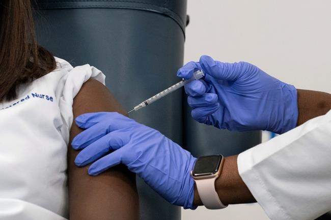 Sandra Lindsay, left, a nurse at Long Island Jewish Medical Center, is inoculated with the Pfizer-BioNTech COVID-19 vaccine by Dr. Michelle Chester, Monday, Dec. 14, 2020, in the Queens borough of New York. (AP Photo/Mark Lennihan, Pool)