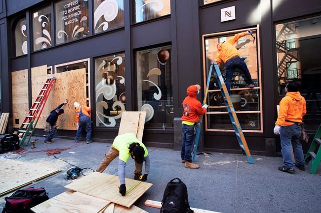 Workers board up windows of a Nespresso store, Monday, June 1, 2020, in the SoHo neighbourhood of New York. Protesters broke into the store Sunday night in reaction to George Floyd's death while in police custody on May 25 in Minneapolis. (AP Photo/Mark Lennihan)
