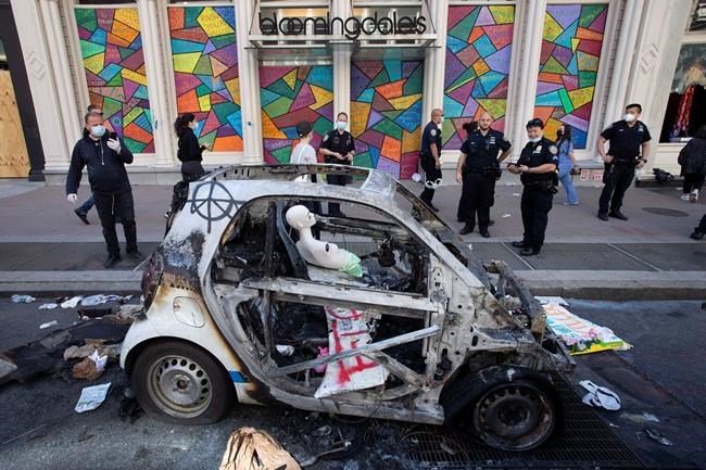 Police officers stop to look at a burned out police car, Monday, June 1, 2020, in the SoHo neighbourhood of New York. Protesters burned the car in reaction to George Floyd's death while in police custody on May 25 in Minneapolis. (AP Photo/Mark Lennihan)